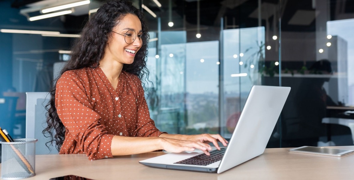 Happy and smiling hispanic businesswoman typing on laptop