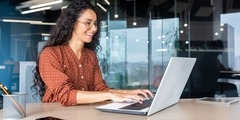 Happy and smiling hispanic businesswoman typing on laptop