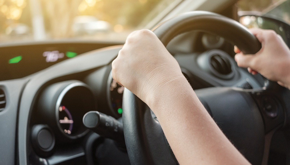 Woman driving her car with both hands on steering wheel