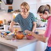 A young woman with hearing aids talking to her mother in the kitchen. They have a breakfast and enjoying the time they spending together.
